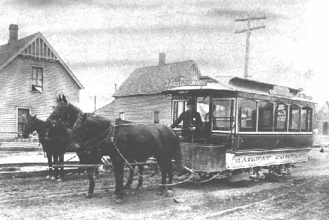 Horse-drawn streetcar passes a wagon